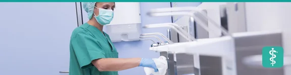 Eine Reinigungskraft säubert im sterilen Raum in Schutzkleidung sorgfältig die Oberflächen.