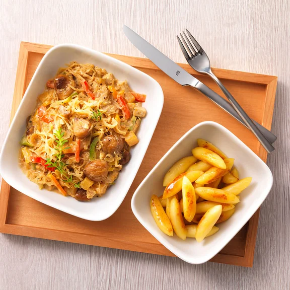 Ein Bild einem weißen Schalen mit Schupfnudeln und ein Salat als inhalt auf einem Holztablett auf einem Tisch