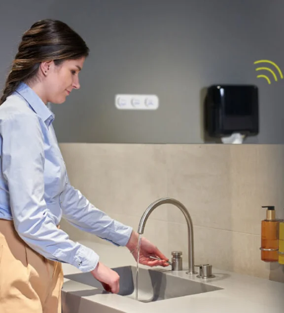 eine Frau wäscht sich die Hände an einem Waschbecken