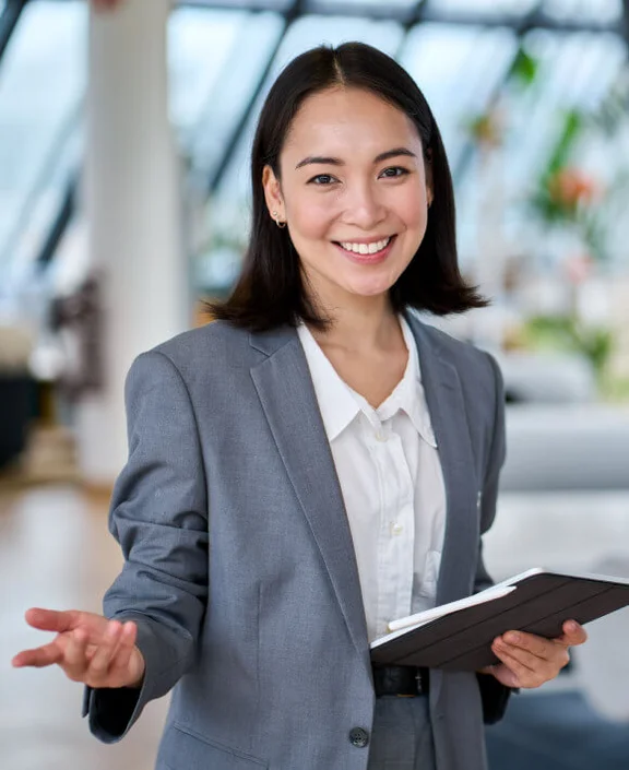 eine lächelnde Frau in einem Business-Outfit mit einem Tablet in ihrer Hand
