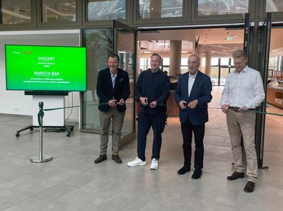 EIn Bild von vier Männern die eine grüne Schleife zur eröffnung des Restaurants zerschneiden im Hintergrund ist das Restaurant Cantinetta