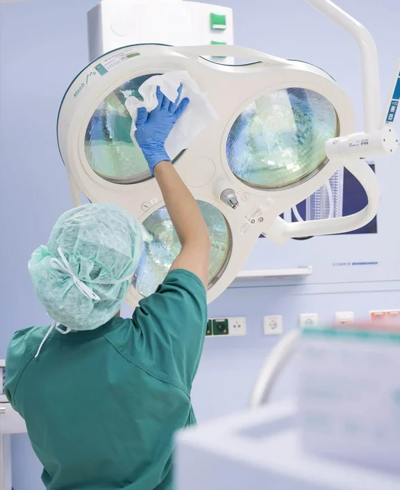 eine Person in OP-Kleidung wischt mit einem Tuch ein OP-Gerät