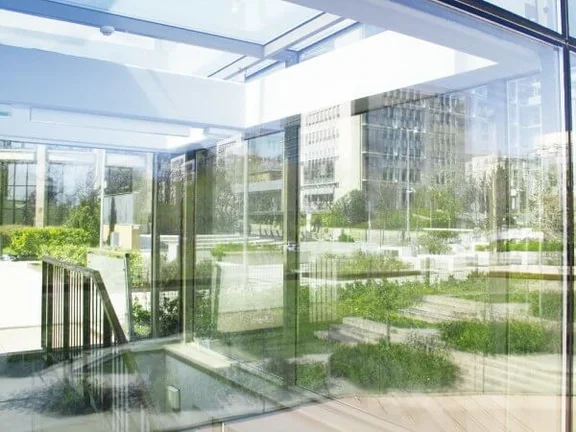 Ein Bild von einem Gebäude mit einer Glasfassade in der sich eine Terasse spiegelt